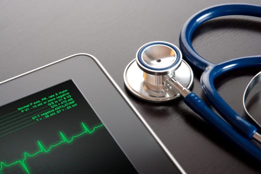 Doctor workplace with tablet display electrocardiogram (ECG) and stethoscope