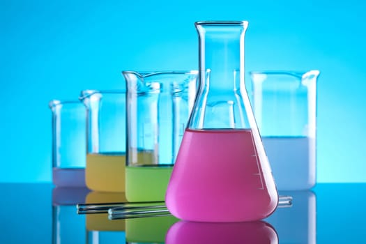 Laboratory Glassware - chemical flasks with colored solution. Focused on front flask with purple solution.