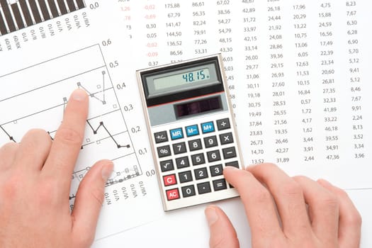 Concept of business analyst - hand with calculating on calculator, sheet and graph from top view