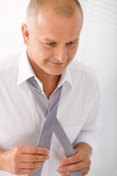 Handsome stylish mature business man tie a tie white shirt