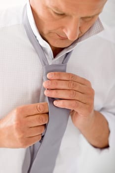 Handsome stylish mature business man tie a tie white shirt