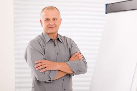 Mature handsome businessman standing in front of empty flip chart