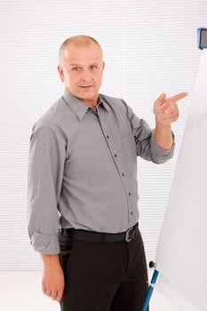 Mature handsome businessman pointing at empty flip chart looking front