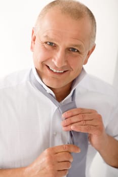 Handsome stylish mature business man smiling tie a tie closeup