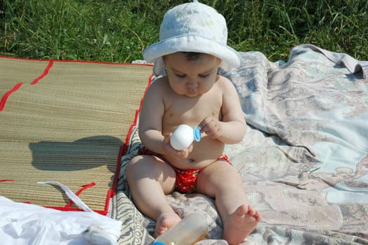 baby with a hat and bottle in the beach