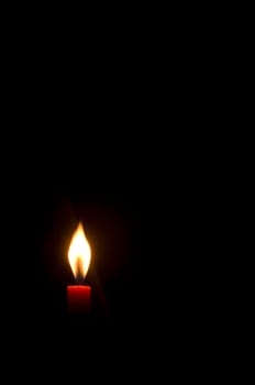 a burning candle in darkness, with copy space.