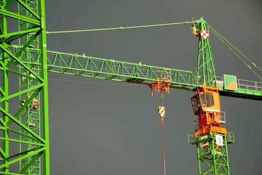 Construction cranes struck by the sun in front of dark clouds