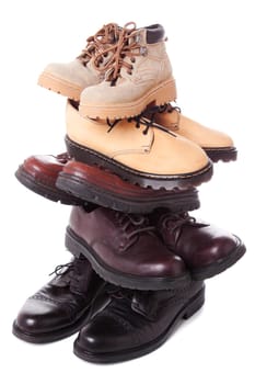 Stack of male leather boots isolated over white background