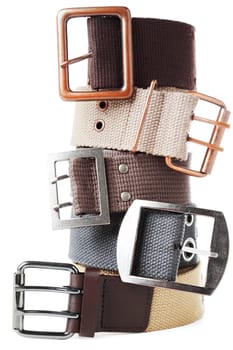 Five textile belts with metal buckles grouped in stack. Isolated over white background