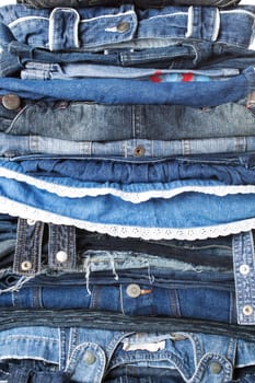 Close-up to huge pile of female and male jeans clothes.