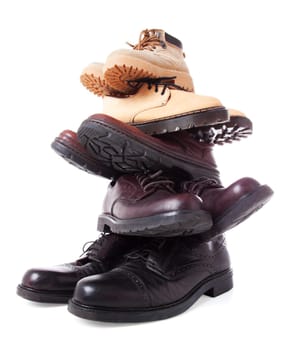 Stack of male leather boots isolated over white background. Low point of view. Wide angle shot