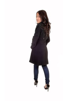 A young Asian woman in a gray winter coat and jeans standing and looking  over her shoulder with long brunette hair, for white background.
