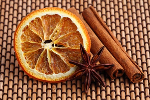 Orange slice,anime sticks and cinnamon sticks on bamboo mat.