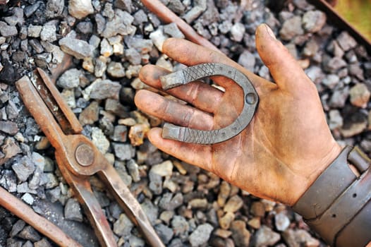 Detail of dirty hand holding horseshoe - blacksmith