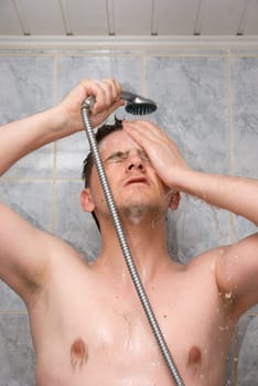 Man having shower in bathroom with soap and shampoo