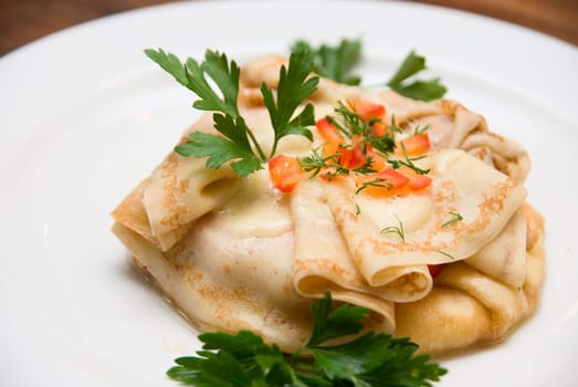 Close up of Pancakes with greenery on white plate at wood table