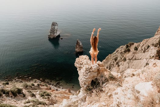 Woman travel sea. Happy tourist taking picture outdoors for memories. Woman traveler looks at the edge of the cliff on the sea bay of mountains, sharing travel adventure journey.