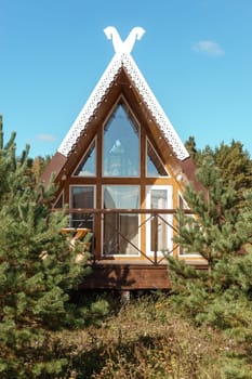 The concept of glamping and renting a chalet for weekend. Wooden house with a veranda in nature around coniferous trees.