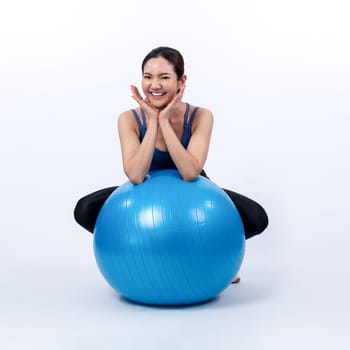 Young attractive asian woman portrait in sportswear with fit ball targeting on abs muscle for effective energetic daily workout routine. Studio shot and isolated background. Vigorous