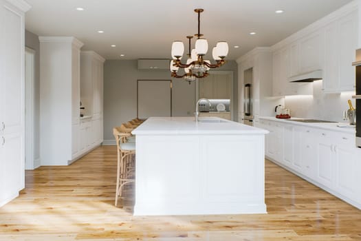 Traditional white kitchen with long island and wooden chairs with varnished wood flooring. Classic kitchen with large chandeliers and kitchen appliances. 3d rendering