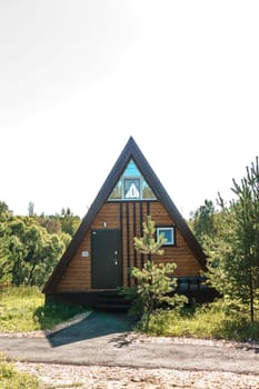 The concept of glamping and renting a chalet for weekend. Wooden house with a veranda in nature around coniferous trees.