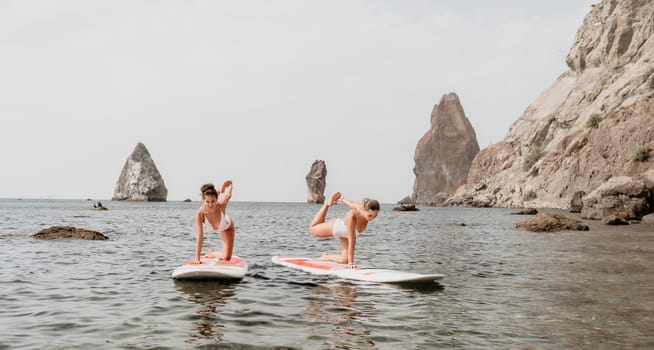 Woman sup yoga. Middle age sporty woman practising yoga pilates on paddle sup surfboard. Female stretching doing workout on sea water. Modern individual hipster outdoor summer sport activity