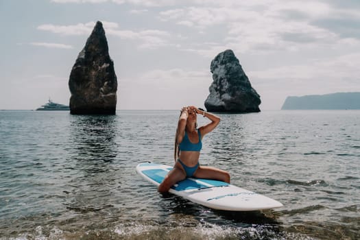 Close up shot of beautiful young caucasian woman with black hair and freckles looking at camera and smiling. Cute woman portrait in a pink bikini posing on a volcanic rock high above the sea