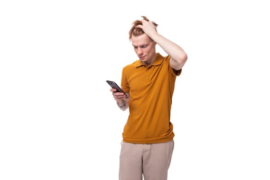 young man with red hair writes a message on the phone.