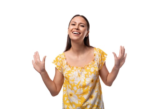 Caucasian young woman with straight black hair smiles welcomingly on a white background.