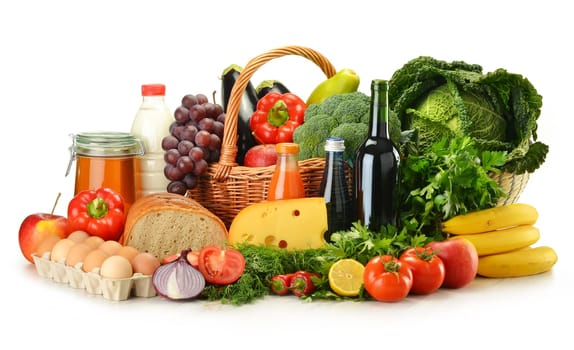 Groceries in wicker basket including vegetables, fruits, bakery and dairy products and wine isolated on white
