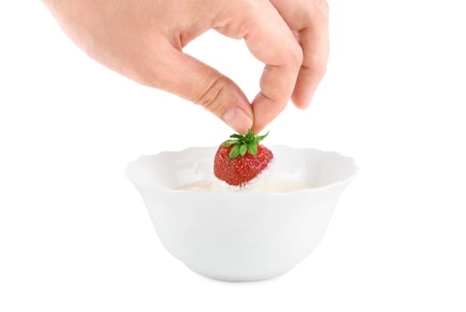 Hand with strawberry in cream on white