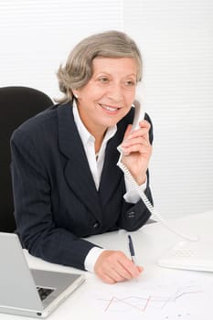 Smiling successful senior businesswoman sitting behind office table portrait