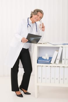 Professional senior doctor female on phone hold x-ray at office