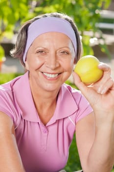 Senior sportive woman smiling eat apple outdoor sunny day