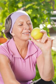 Senior sportive woman smiling eat apple outdoor sunny day
