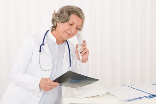 Senior doctor female on phone watch down x-ray at office