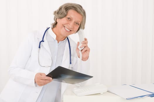 Professional senior doctor female on phone hold x-ray at office
