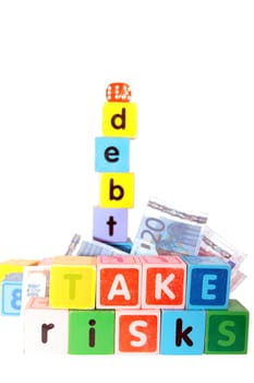 assorted childrens toy letter building blocks against a white background that spell take risks and debt