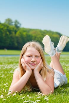 Blond teenager girl lying on the grass in a sunny day