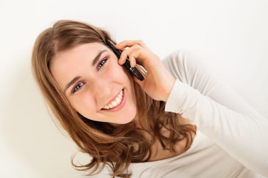 Tilted portrait of happy young woman talking on her cell phone
