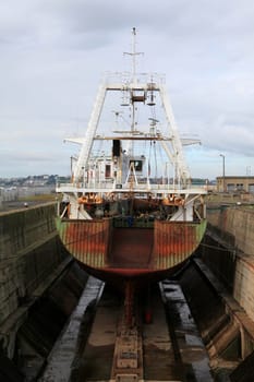 Fishing ship ready for repairs in a large, dry dock