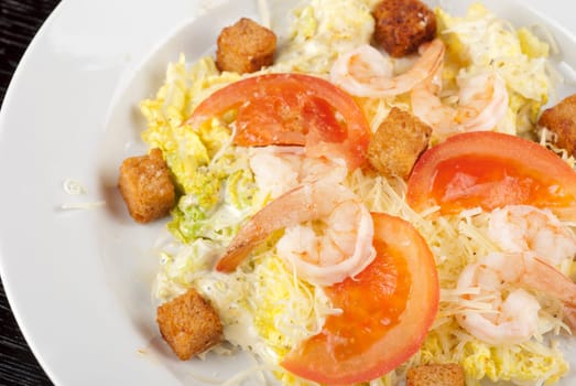 Salad of tiger shrimps, lettuce, chinese cabbage, tomato, garlic rusk, parmesan cheese and sauce