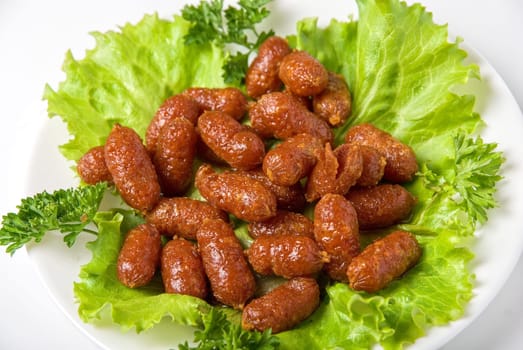roasted tasty sausages on green lettuce with isolated on white