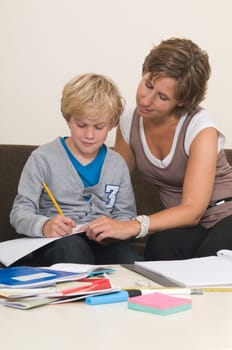 Boy is doing his homework in the livingroom while mother is helping him