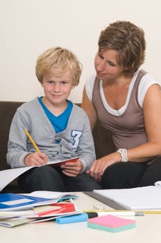 Boy is doing his homework in the livingroom while mother is helping him