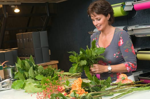 Female florist working in a flower store, making the bouquet ready for the customer