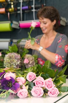 Female florist working in a flower store, making the bouquet ready for the customer