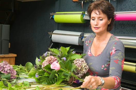 Female florist working in a flower store, making the bouquet ready for the customer