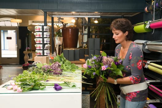 Female florist working in a flower store, making the bouquet ready for the customer