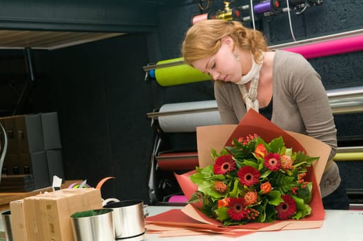 Female florist working in a flower store, making the bouquet ready for the customer